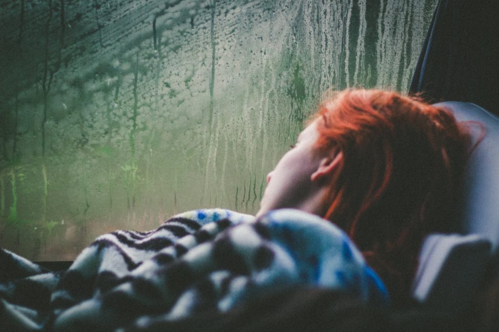 a person lying beside a misty vehicle window