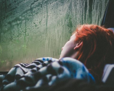 a person lying beside a misty vehicle window