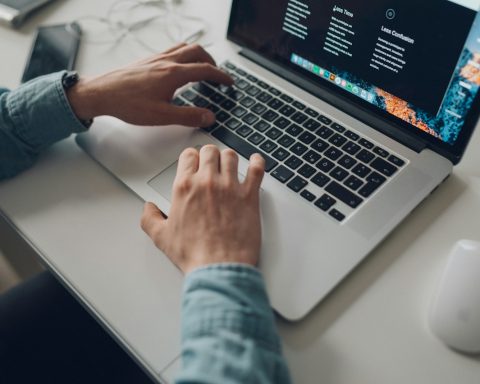 person wearing long-sleeve top working on laptop