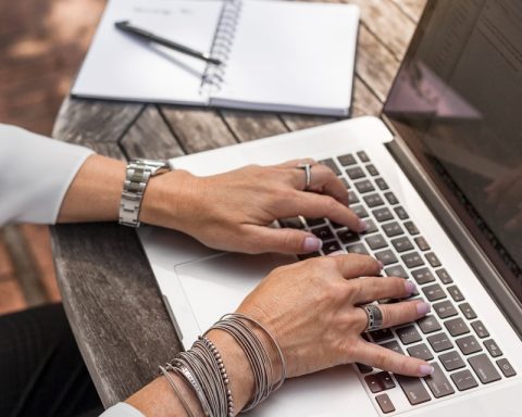 person typing on MacBook Pro on brown wooden table during daytime photo