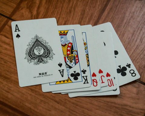 A close-up view of playing cards on a wooden surface, featuring an ace of spades.