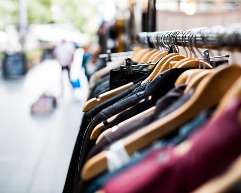 Kleurrijke vintage kleding hangend aan een rek in een kringloopwinkel